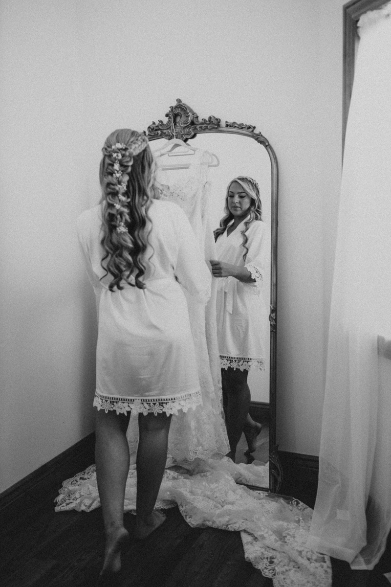Photography Studio on Main, a woman stands before a mirror about to try on a wedding dress hanging before it