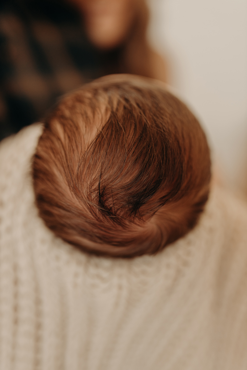 Newborn Photography, a baby being held wrapped in a blanket with a full head of hair