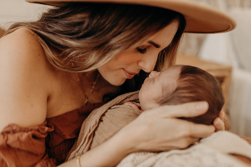 Newborn Photography, a mother draws nose to nose with her sweet little baby