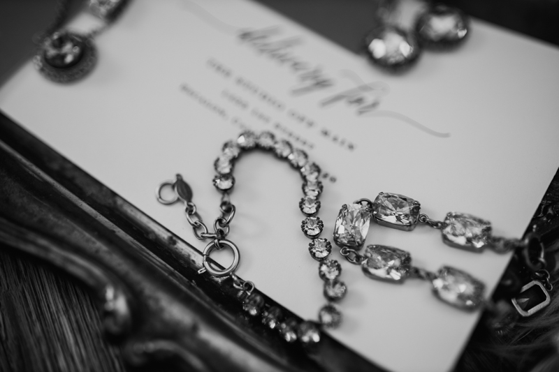Photography Studio on Main, necklaces adorned with jewels and diamonds sit atop a wedding invitation