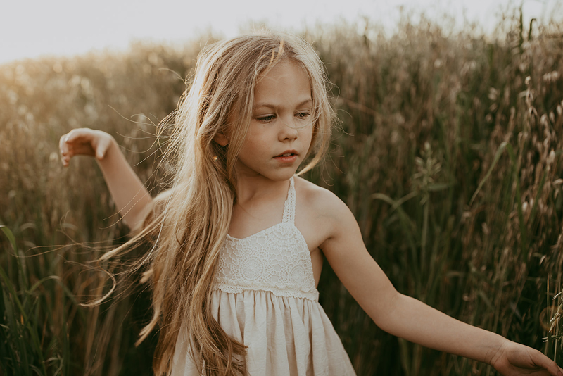 Family Photography, a little girl in a white dress walks through tall grass