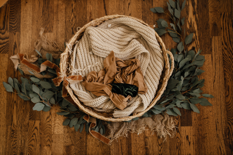 Photography Studio on Main, a wicker basket sits on a floor containing woven throw blankets
