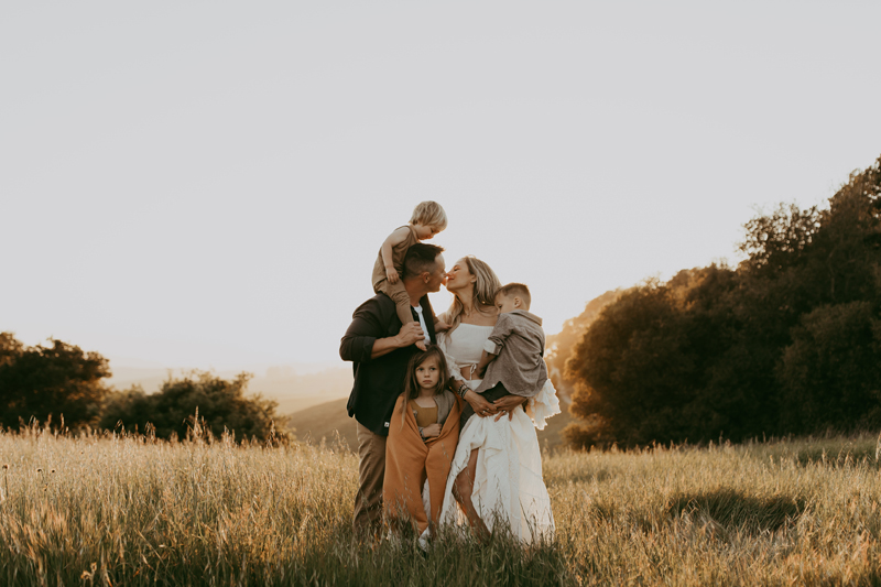 Family Photography,  a family of five stand in a dry grassy meadow at golden hour