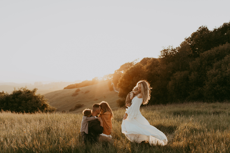 Family Photography, a family of five all draw close on a grassy hillside at golden hour