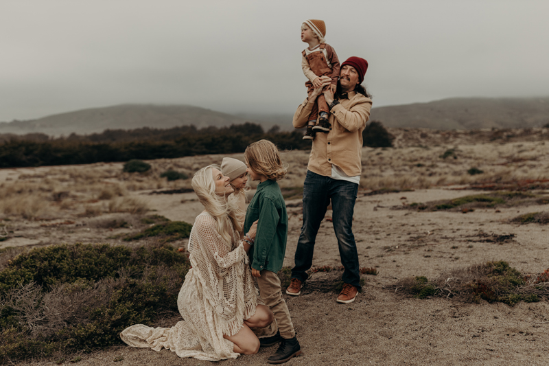 Family Photography, on a beach on a foggy day, a young family all appreciate each other, mom looking int o young son's eyes, dad holding the youngest on his shoulders