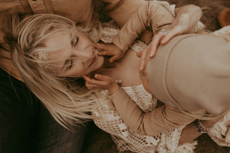 Family Photography, a mother holds her baby above her as she lays in her husband's laps