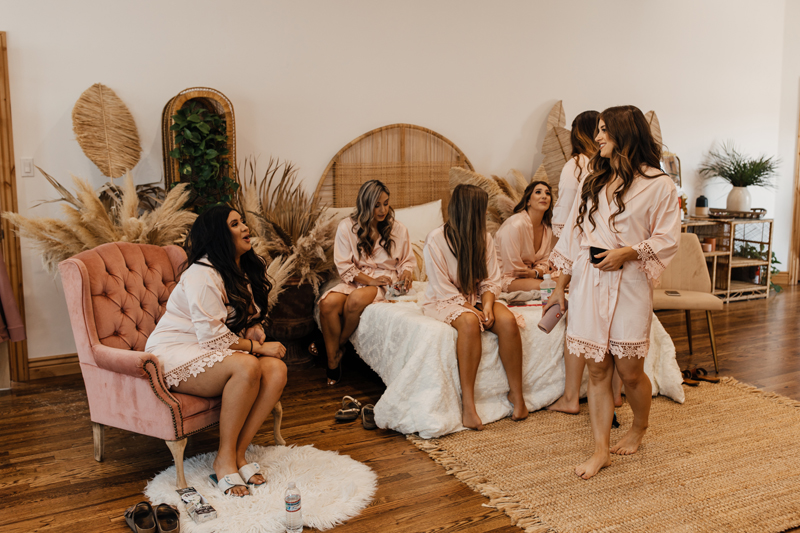 Photography Studio on Main, a group of bridesmaid sit comfortably around a boho style room, the bride in a comfy chair near them